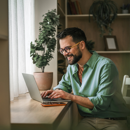 Smiling man working on laptop in a modern workspace