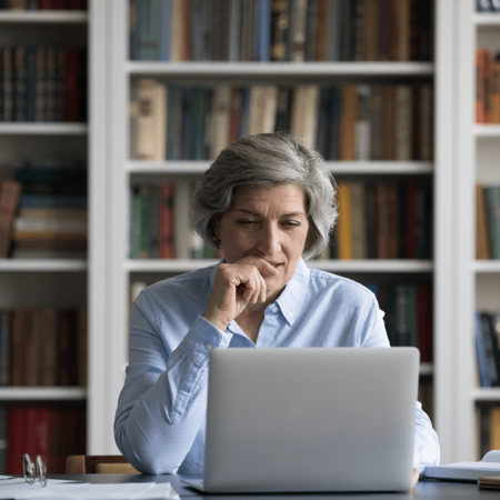 Thinking woman looking at a laptop