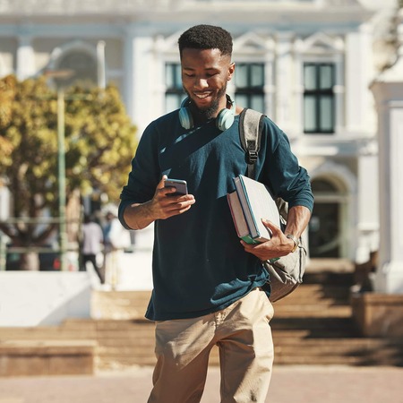 Man walking through campus looking at his mobile phone