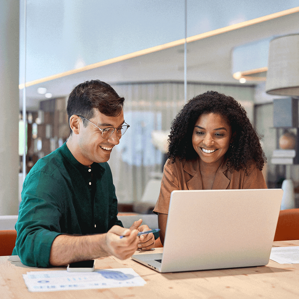 Two people smiling and collaborating during a performance review on a laptop