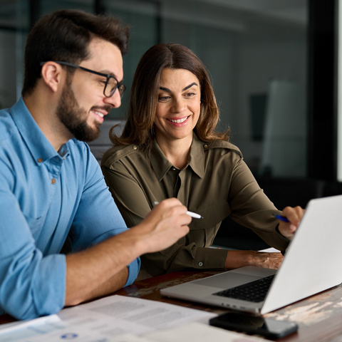 Co-workers looking at laptop smiling
